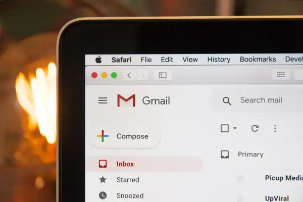 Przykładowy e-mail po angielsku z tłumaczeniem na ekranie laptopa. Widoczny interfejs Gmail i pasek Safari.