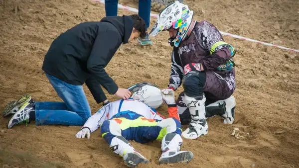 Po wypadku Tomasza Golloba, ratownicy udzielają pomocy leżącemu na piasku zawodnikowi w stroju motocyklowym.