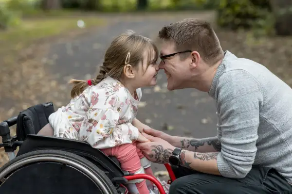 Padre e figlia si toccano il naso, lei in carrozzina. Un momento di gioia che celebra i diritti genitori con figlio disabile.