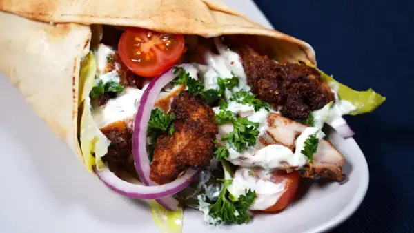 En saftig kyckling shawarma i pitabröd med tomater, lök, sallad och vit sås.