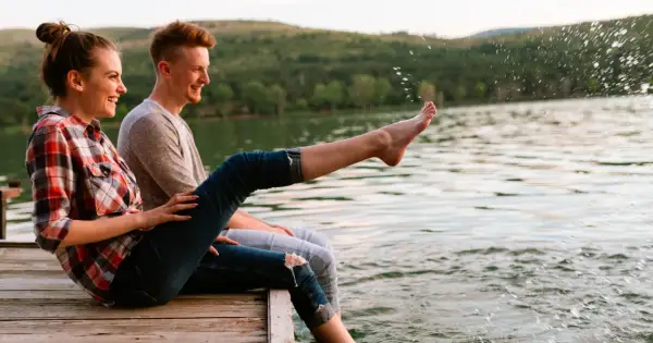 Para spędza czas nad jeziorem, ciesząc się słońcem i wodą. Ich beztroska przypomina o potrzebie ubezpieczenia podstawowego TUiR.