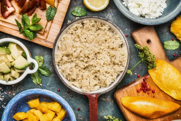 Quinoa quellen lassen ohne kochen: Ein Teller mit gekochter Quinoa, daneben Avocado, Mango, Tomaten, Feta und Minze.