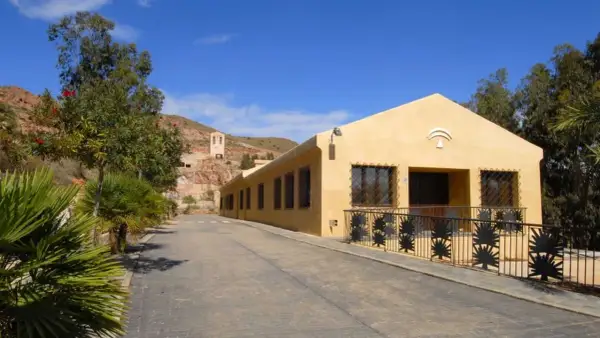 La casa de los volcanes, un edificio amarillo con rejas de palmeras, se alza bajo un cielo azul.