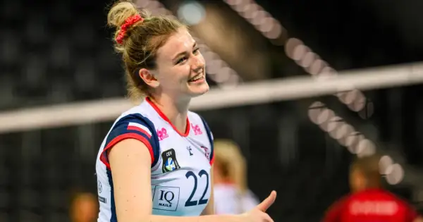 Uśmiechnięta siatkarka Natalia Lijewska w białej koszulce z numerem 22, z czerwoną opaską na włosach, podczas meczu.