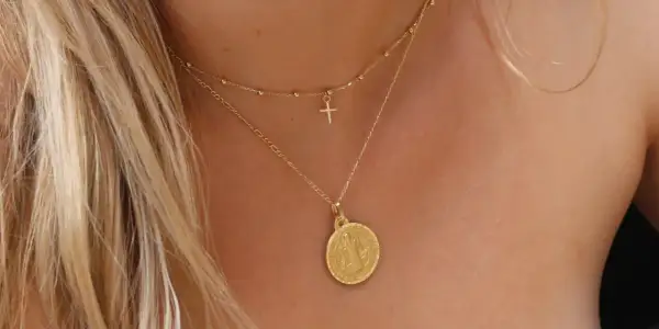 Elegante cadena de oro con medalla de San Benito y un pequeño crucifijo.