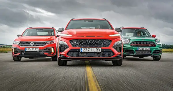 Trzy sportowe małe SUV-y: czerwony Volkswagen, pomarańczowy Hyundai i zielony Mini, jadące po drodze.