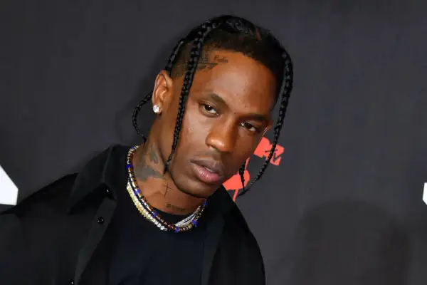 Travis Scott w czarnej koszuli i naszyjnikach, z warkoczami. Fani w Polsce czekają na jego koncert.