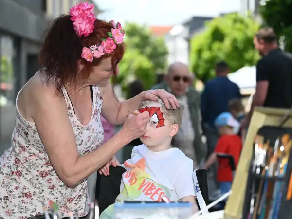 Kind wird beim Stadtfest in Radevormwald von einer Frau mit Spiderman-Maske bemalt.