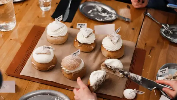 En härlig samling semlor med fluffig grädde och flaggor. En semla är uppskuren, redo för en smak av ritorno semla.