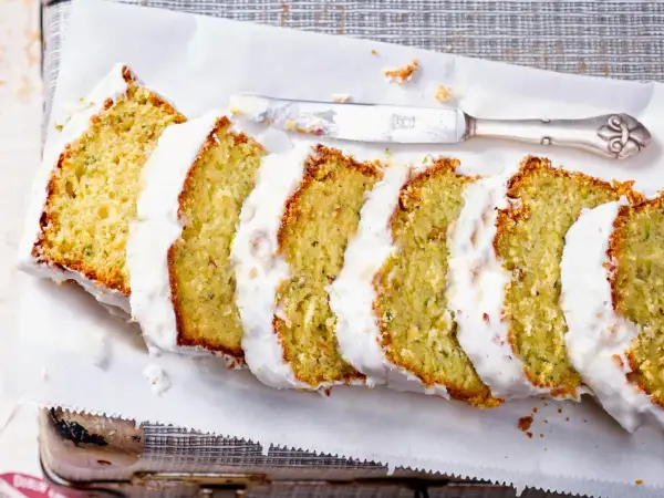 Saftiger Zucchini Kuchen mit weißer Glasur, in Scheiben geschnitten, bereit zum Genießen.