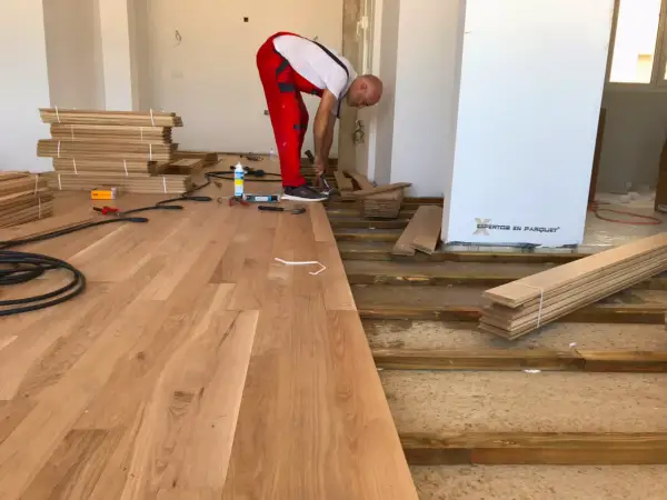 Instalador coloca elondo madera en un suelo.