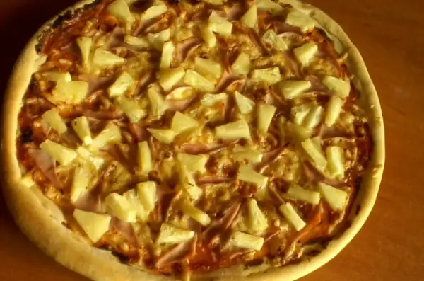 Pyszna pizza z ananasem i szynką, zrumieniona skórka i złocisty ser.