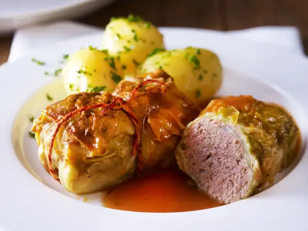 Herzhafte Kohlrouladen mit Kartoffeln, ein Klassiker der deutschen Gerichte, serviert auf einem weißen Teller.