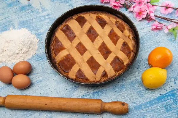 Pastiera appena sfornata con un reticolo di pasta frolla. Quante strisce sulla pastiera? Otto, per un dolce perfetto.