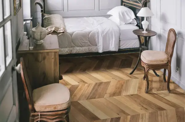 Sypialnia z łóżkiem i meblami, podłoga w jodełkę z kolekcji Marazzi Treverksoul Neutral.