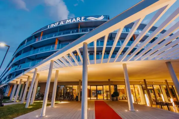 Nowoczesny hotel Infa Mare z charakterystycznym zadaszeniem i czerwonym dywanem zaprasza do swojego wnętrza.
