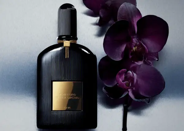 Elegancka butelka perfum Tom Ford Black Orchid 100ml obok ciemnofioletowych storczyków.