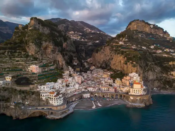 Un borgo pittoresco sulla Costiera Amalfitana, tra i paesi più belli d'Italia, aggrappato alla roccia con case colorate e mare blu.
