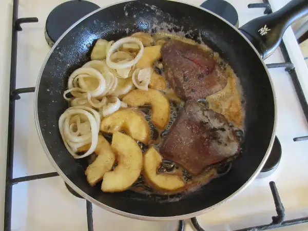 Leber braten: Zwiebelringe und Apfelspalten in der Pfanne mit der Leber garen.
