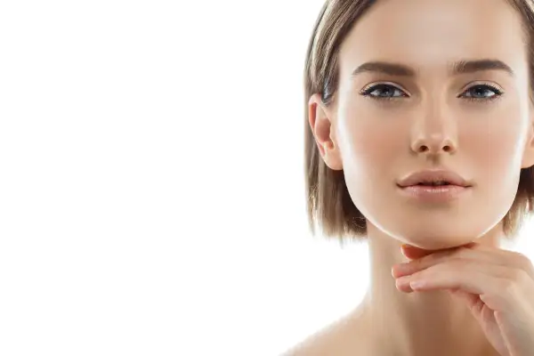 Primo piano di una donna con pelle luminosa e un tocco sul mento, un'ispirazione per chi cerca come snellire il viso con un look naturale.