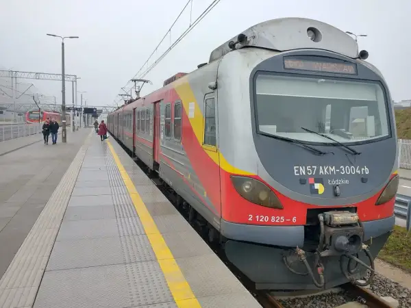 Pociąg EN57 AKM-3004rb z napisem "WARSZAWA" na stacji. Sprawdź rozkład jazdy Nowy Dwór Mazowiecki, aby zaplanować podróż.