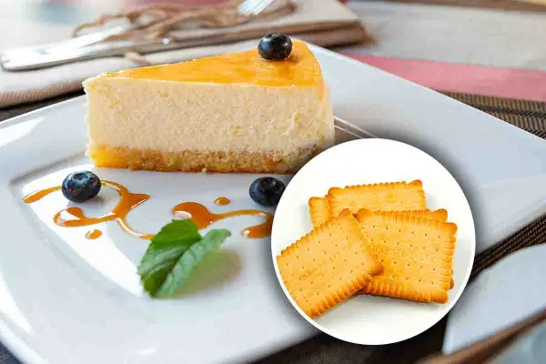 Una fetta di cheesecake con topping giallo, mirtilli e salsa caramello, accompagnata da biscotti secchi. Diversi tipi di cheesecake per ogni gusto.