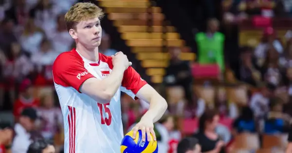 Młody siatkarz Jakub Kochanowski, numer 15, w biało-czerwonej koszulce reprezentacji Polski, z piłką w dłoni. Jego wzrost robi wrażenie.