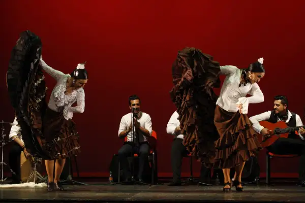Bailarinas de flamenco con volantes, guitarrista y percusionista. La pasión del flamenco, su saeta significado, cobra vida en el escenario.