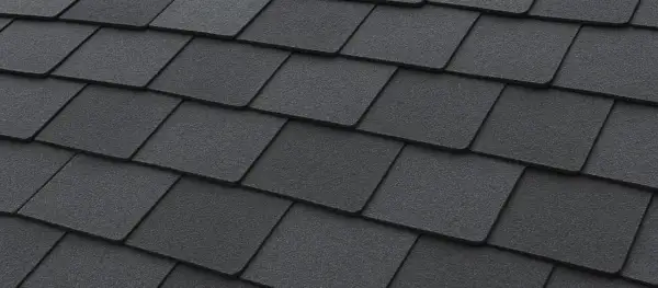 Close-up of dark grey, textured recycled shingles on a roof, showcasing their layered pattern and durable appearance.