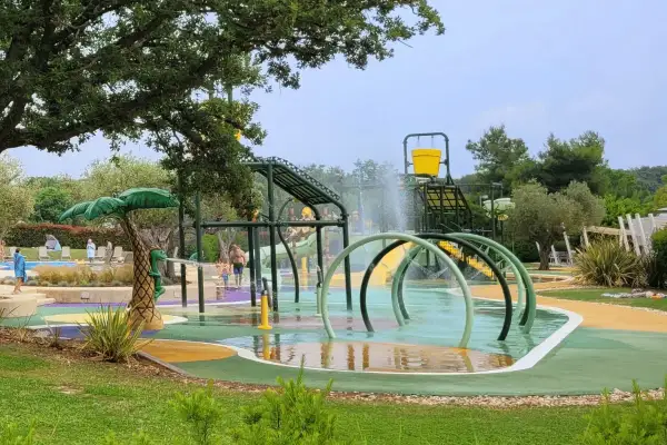 Wesoły wodny plac zabaw z palmą i zjeżdżalniami, idealny na **camping dla dzieci**.