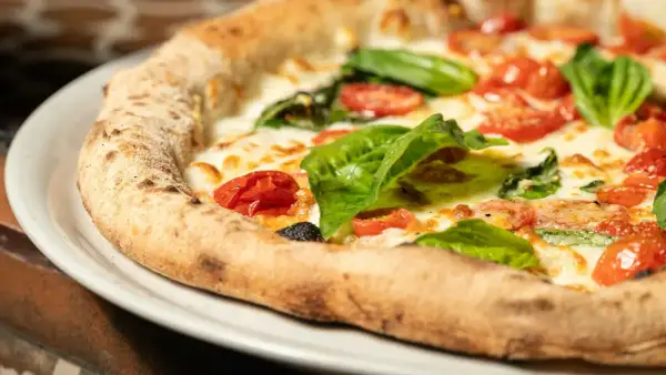 Pyszna pizza Margherita, klasyk kuchni włoskiej, z pomidorkami, mozzarellą i bazylią. Idealna pizza wlochy.