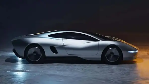 Elegancki, srebrny, nowy jaguar o futurystycznym designie, z wąskimi światłami LED i aerodynamiczną sylwetką, stoi na mokrej nawierzchni.