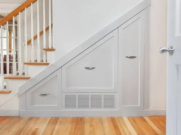 Solución inteligente para hacer armario bajo escalera. Muebles blancos a medida aprovechan cada rincón.