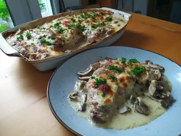 En krämig grekisk pyttipanna med svamp och gratinerad ost, toppad med persilja. Serveras i en ugnsform och på en tallrik.