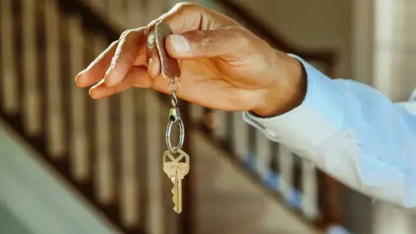 Chiave di casa tenuta in mano, simbolo di un immobile intestato ad un solo coniuge in comunione dei beni.