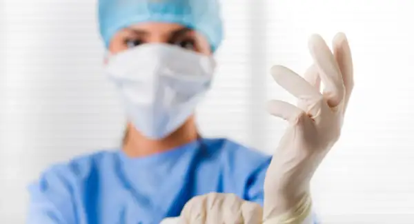 Ärztin zieht Handschuhe an. Der PSA-Wert ist wichtig für die Sicherheit.