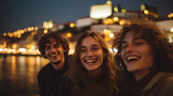 Tre amici ridono felici, immersi nella magica atmosfera del porto vita notturna, con le luci sfocate della città a fare da sfondo.
