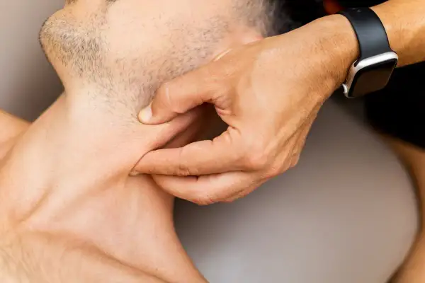 Mano che palpa il collo, evidenziando un punto di dolore al tatto.
