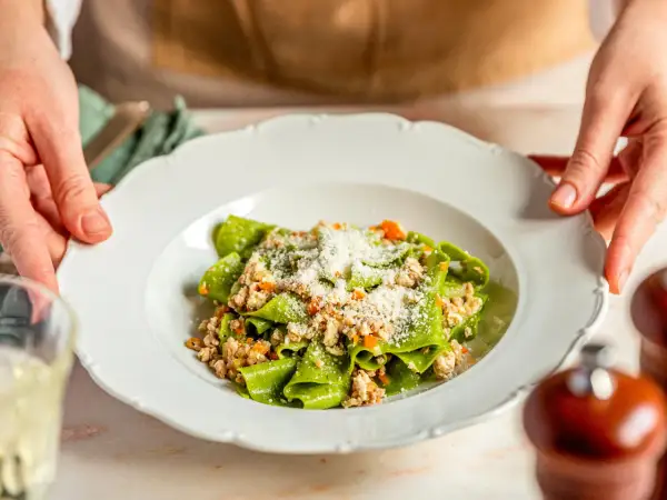 Grüne Bandnudeln mit einem herzhaften ragu bianco, bestreut mit Parmesan.