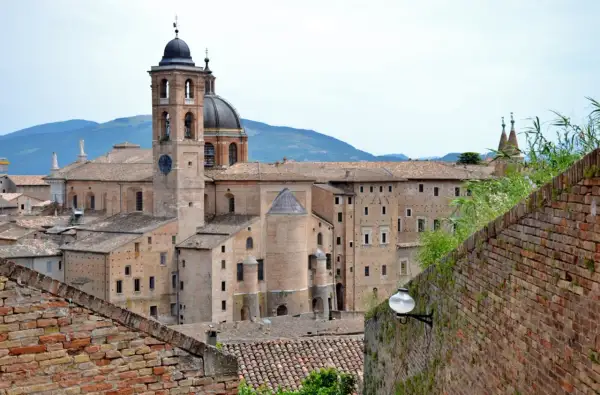 La maestosa corte di Urbino, con il suo campanile e la cupola, si staglia contro le colline.