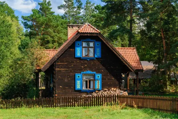 Drewniany dom z niebieskimi okiennicami, idealny na wypoczynek z podlaskim bonem turystycznym 2026.