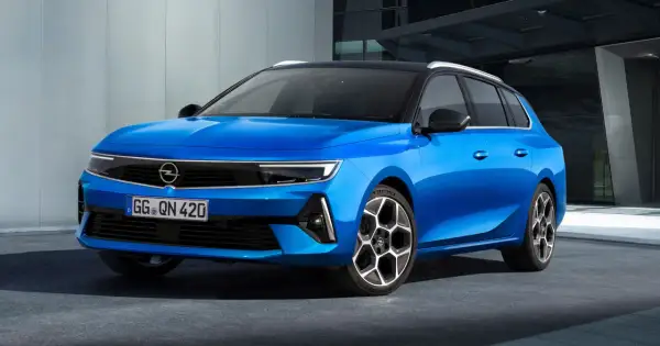 Błękitny Opel Astra Sports Tourer z czarnym dachem i felgami stoi przed nowoczesnym budynkiem.