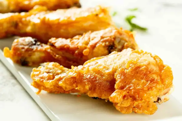 Muslos de pollo crujientes y dorados, recién salidos de la freidora de aire. Perfectos para una comida rápida y deliciosa.