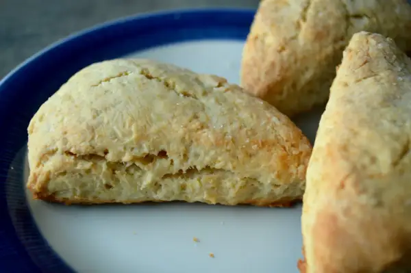 Tre gyllene scones, bakade med bakpulver, ligger på en tallrik med blå kant.