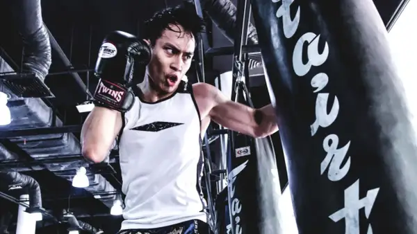 A boxer trains intensely, focusing on his boxing breathing as he punches a heavy bag.