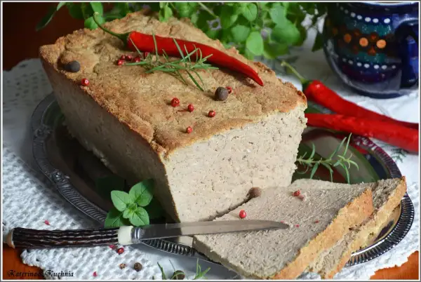 Pyszny pasztet mieszany drobiowo-wieprzowy, udekorowany papryczką chili i ziołami, gotowy do podania na kromce chleba.