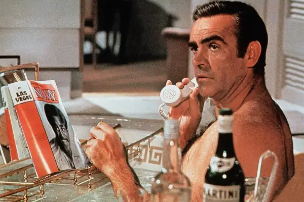 Sean Connery jako James Bond, w wannie, rozmawia przez telefon, obok butelka Martini wstrząśnięte nie mieszane i magazyn "Now".
