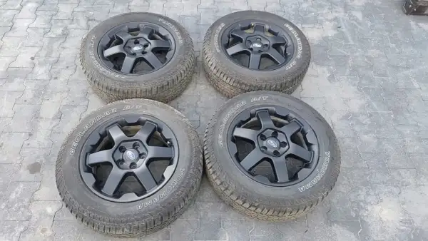 Cztery czarne felgi z oponami Yokohama Geolandar A/T, idealne do Subaru Outback Wilderness, gotowe na każdą przygodę.