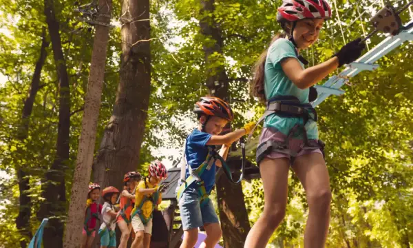Dzieci w kaskach pokonują park linowy, świetna zabawa i **bieszczady atrakcje dla dzieci**.