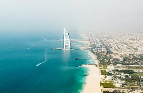 Widok z lotu ptaka na plaże w Dubaju, z charakterystycznym hotelem Burdż al-Arab i turkusową wodą.